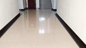 A hallway with a shiny tiled floor, a red door at the end, and a staircase leading to an upper level. - Bingyugou Jiahua Business Hotel (Zhuanghe)