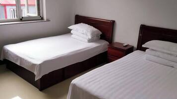 Two single beds with wooden headboards, a nightstand, and a window.