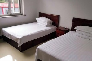 Two single beds with wooden headboards, a nightstand, and a window. - Bingyugou Jiahua Business Hotel (Zhuanghe)