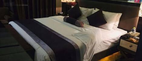 A hotel room with a bed, nightstand, lamp, and a wall with a floral design.