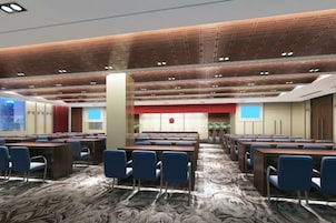 A conference room with multiple tables and chairs, a patterned carpet, and a modern ceiling design.