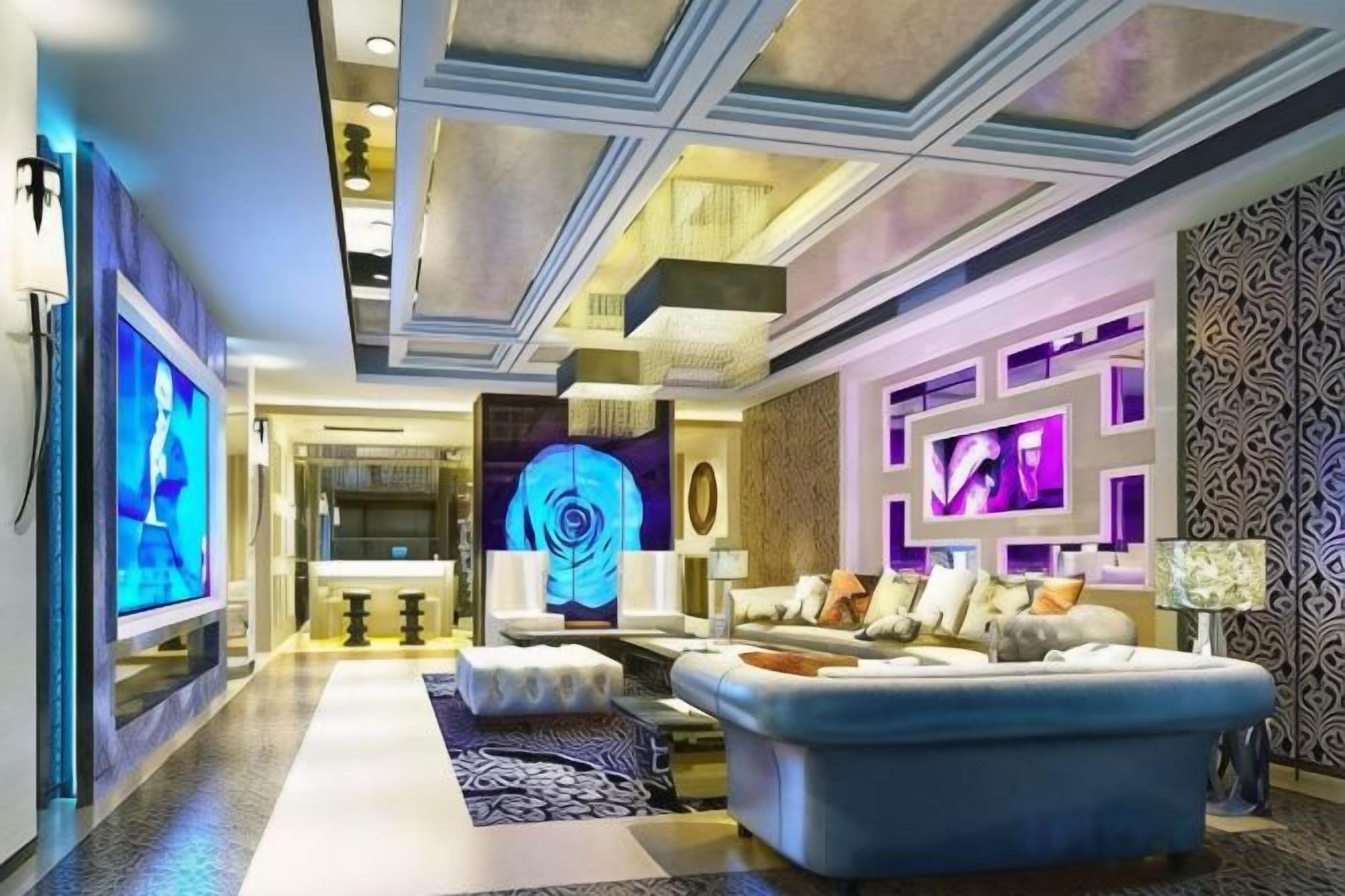 A modern living room with a large blue sofa, a flat-screen TV, and a decorative wall with geometric patterns.