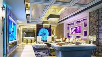 A modern living room with a large blue sofa, a flat-screen TV, and a decorative wall with geometric patterns.