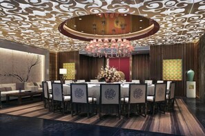 A round dining table with chairs, a chandelier, and a red accent wall.