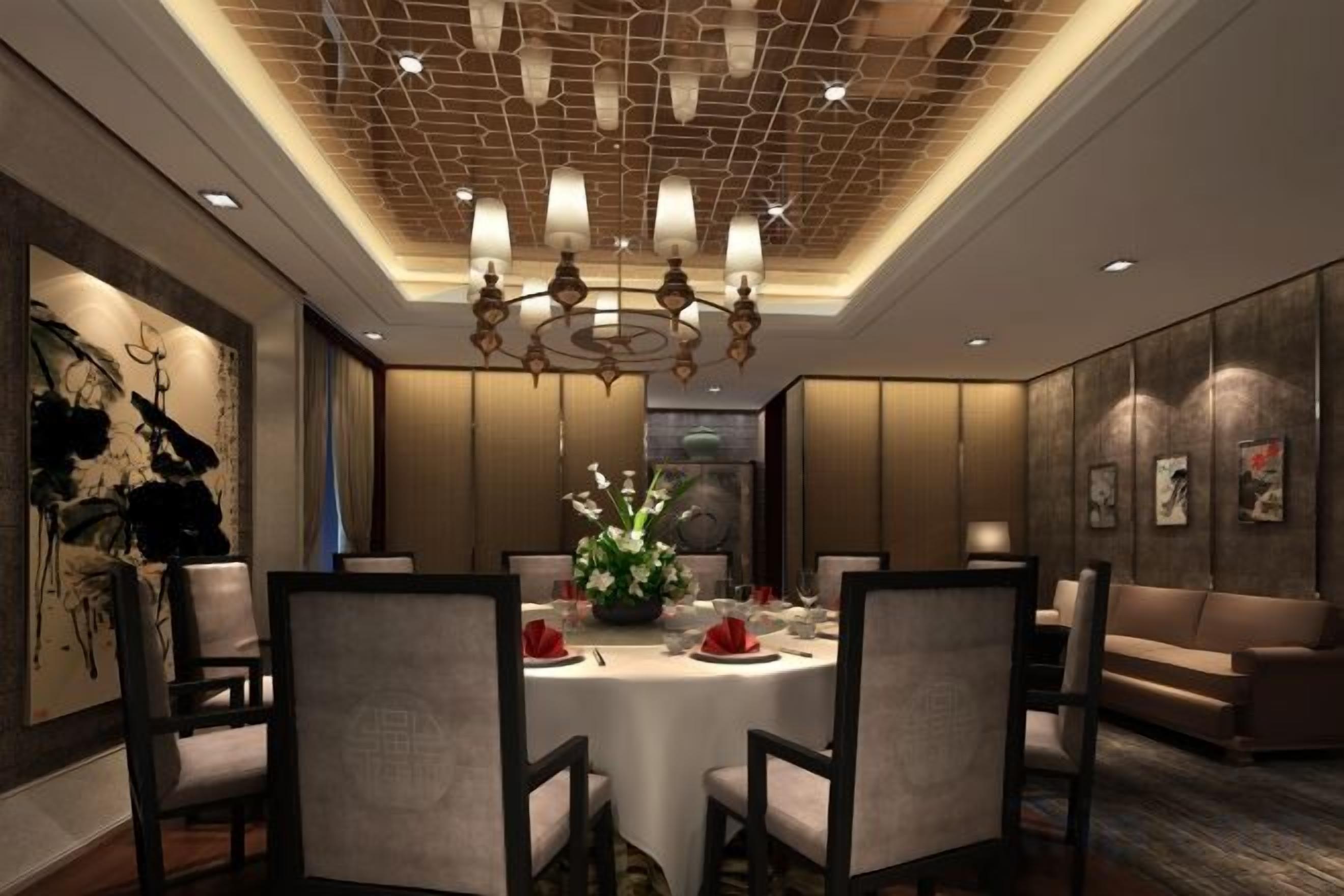 A dining area with a round table, chairs, a chandelier, and artwork on the walls.