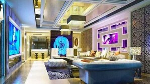 A modern living room with a sofa, a coffee table, and a TV. There is a patterned wall and a chandelier. - Qingtengyuan Hotel (Binzhou)