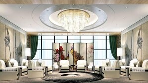 Un hall d'entrée luxueux, agrémenté d'un grand lustre, d'un espace salon et d'une grande fenêtre ornée d'œuvres d'art.