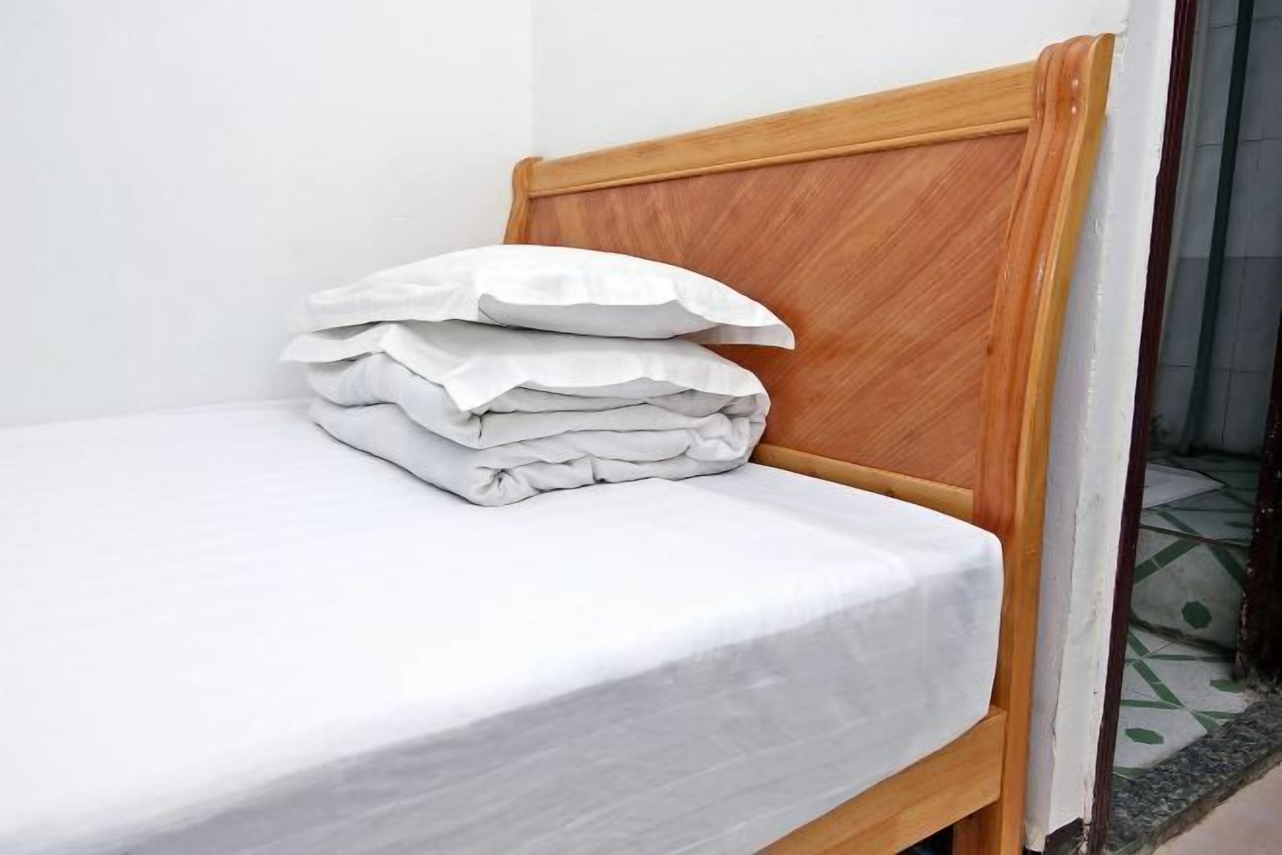 A bed with a wooden headboard and white bedding.
