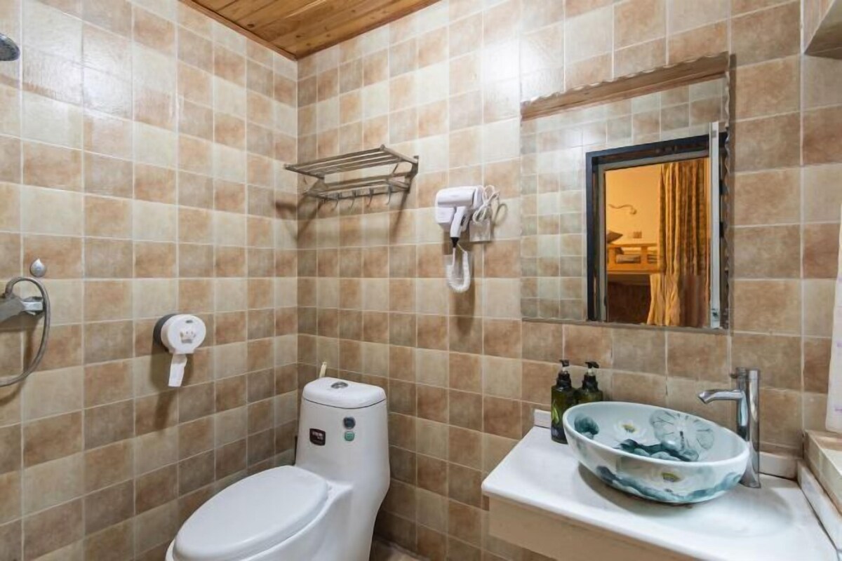 Un bany amb vàter, un lavabo, una barra de tovalloles, un mirall i una zona de dutxa.