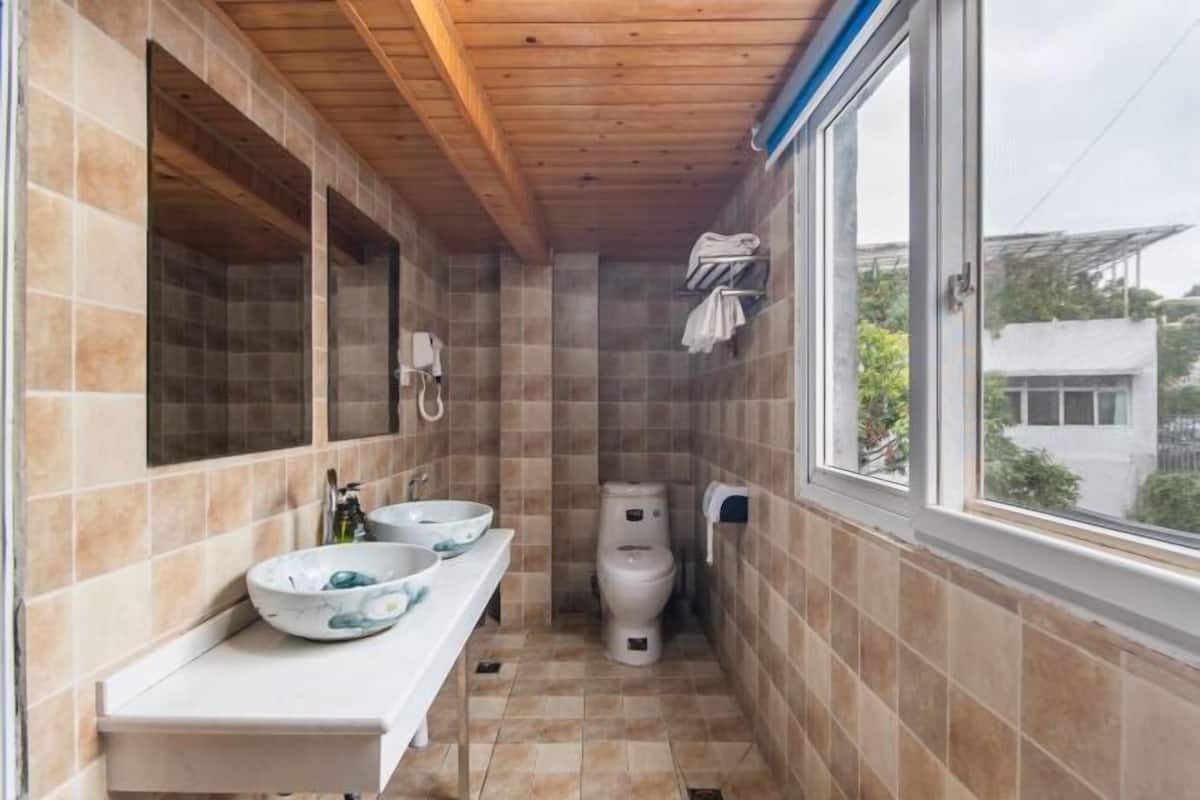 Une salle de bain avec deux lavabos, des toilettes et une fenêtre.