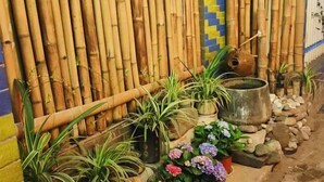 A bamboo wall with potted plants and a large metal container. - Xi Chang Blooming Azalea Hostel (Xichang)
