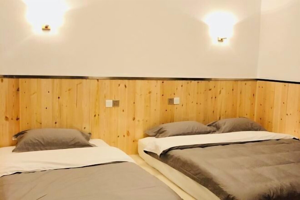 Una habitació amb dos llits, panells de fusta a les parets i il·luminació penjada a la paret.
