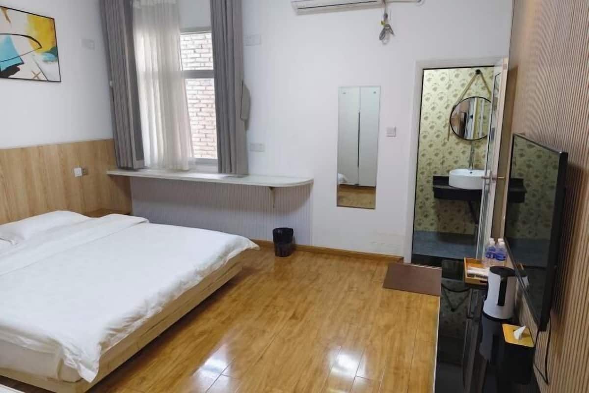 Une chambre d’hôtel avec un lit, une fenêtre avec des rideaux, un miroir, un lavabo et une télévision.