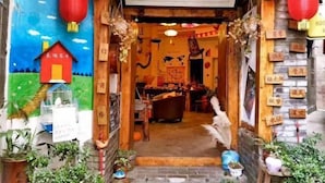 A traditional Chinese restaurant entrance with a signboard, wooden decorations, and potted plants. - Xi Chang Blooming Azalea Hostel (Xichang)