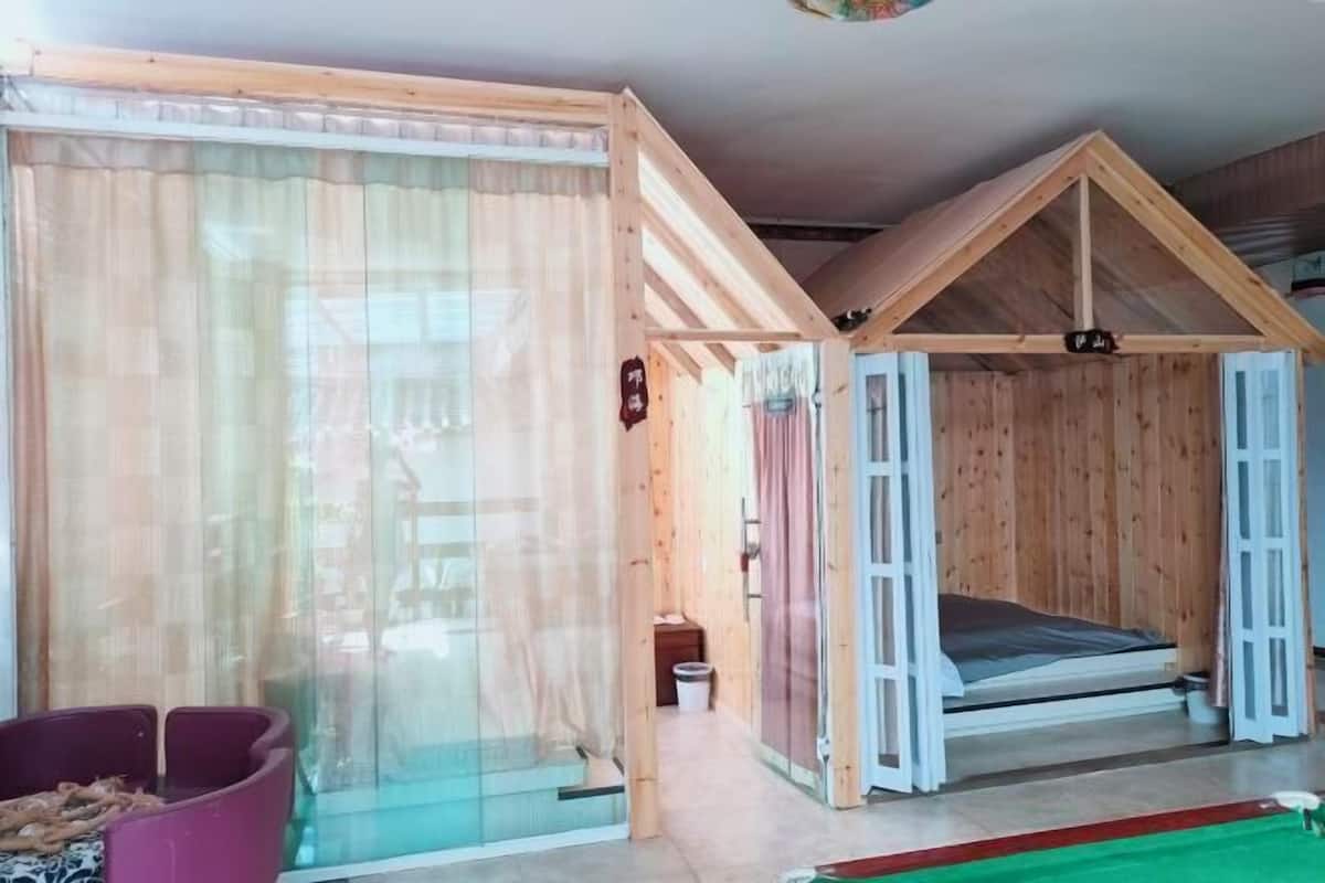 Une pièce en bois avec un lit, une petite table et une fenêtre avec des rideaux.