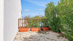 A white building with a gravel patio, potted plants, and a wooden fence. - Apartment 'Con Vista Porto Taverna' with Sea View, Private Terrace and Air Conditioning (Monte Petrosu)