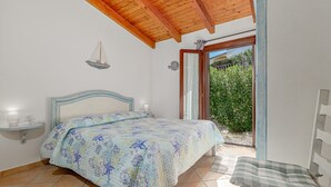 A bedroom with a bed, bedside table, and a view of the outdoors. - Apartment 'Con Vista Porto Taverna' with Sea View, Private Terrace and Air Conditioning (Monte Petrosu)