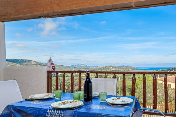 A table set for two with a view of the sea and hills.