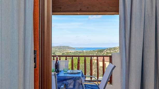 An open balcony with a table and chairs, overlooking a scenic landscape. - Apartment 'Con Vista Porto Taverna' with Sea View, Private Terrace and Air Conditioning (Monte Petrosu)