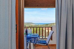 Un balcón abierto con una mesa y sillas, con vistas a un paisaje pintoresco.