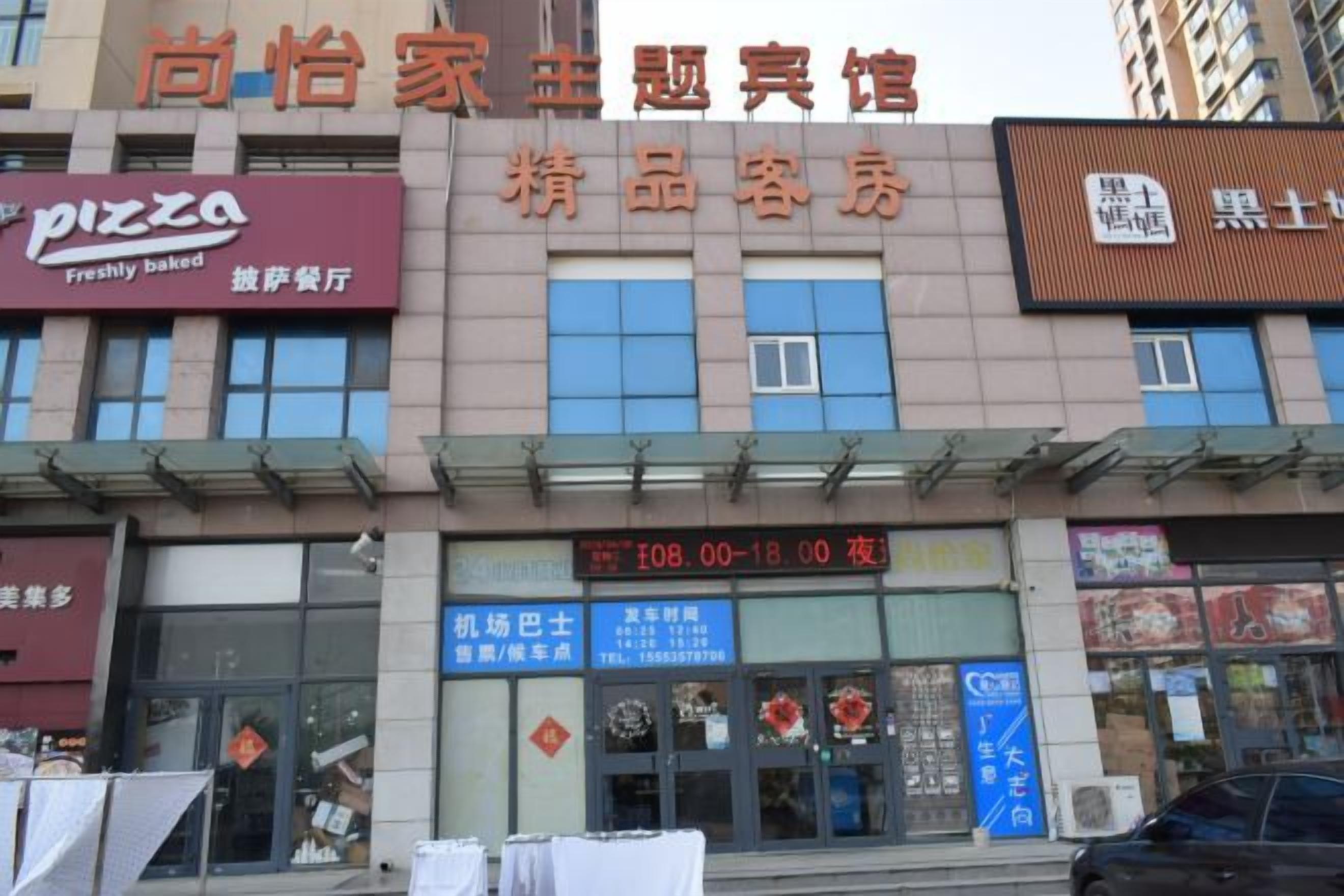 A building with multiple storefronts, including a pizza place and a specialty food restaurant.