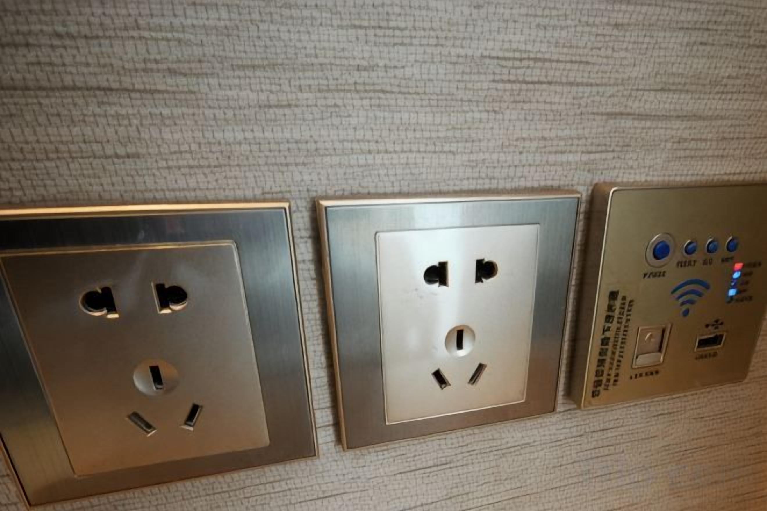 Tres tomas de corriente en una pared con textura, con un panel de control que incluye un botón de encendido y un puerto USB.