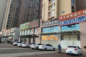 A commercial street with multiple storefronts, including a telecommunications service provider and a car service center. - Shangyijia Themed Hostel (Yantai)