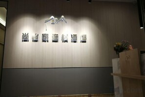 A hotel sign with a modern design, featuring a logo and Chinese characters. - Shangyijia Themed Hostel (Yantai)