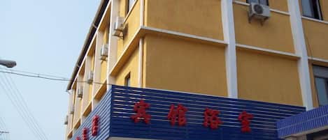 A building with a yellow facade and a blue and red sign.