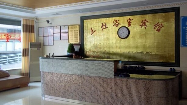 A reception desk with a clock, framed certificates, and a large window with curtains. - Sanzao Hostel (Shanghai)