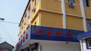A building with a yellow facade and a blue awning. - Sanzao Hostel (Shanghai)