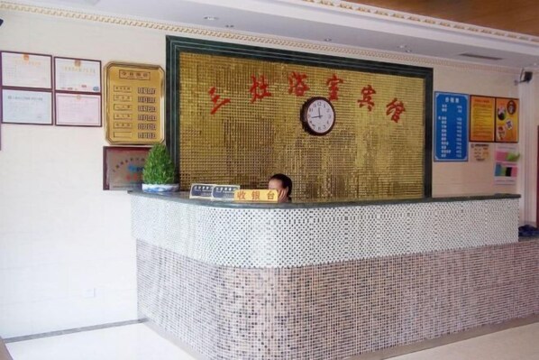 Un mostrador de recepción con un reloj, certificados y una pared grande con caracteres chinos.