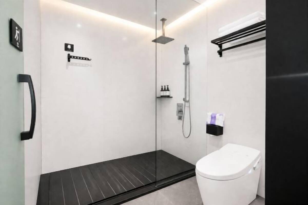 Ein modernes Badezimmer mit einer gläsernen Duschkabine, einer weißen Toilette und einem schwarzen Waschbecken.