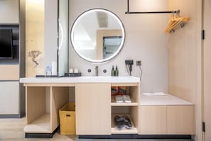 A modern bathroom with a round mirror, built-in shelves, and a towel rack.