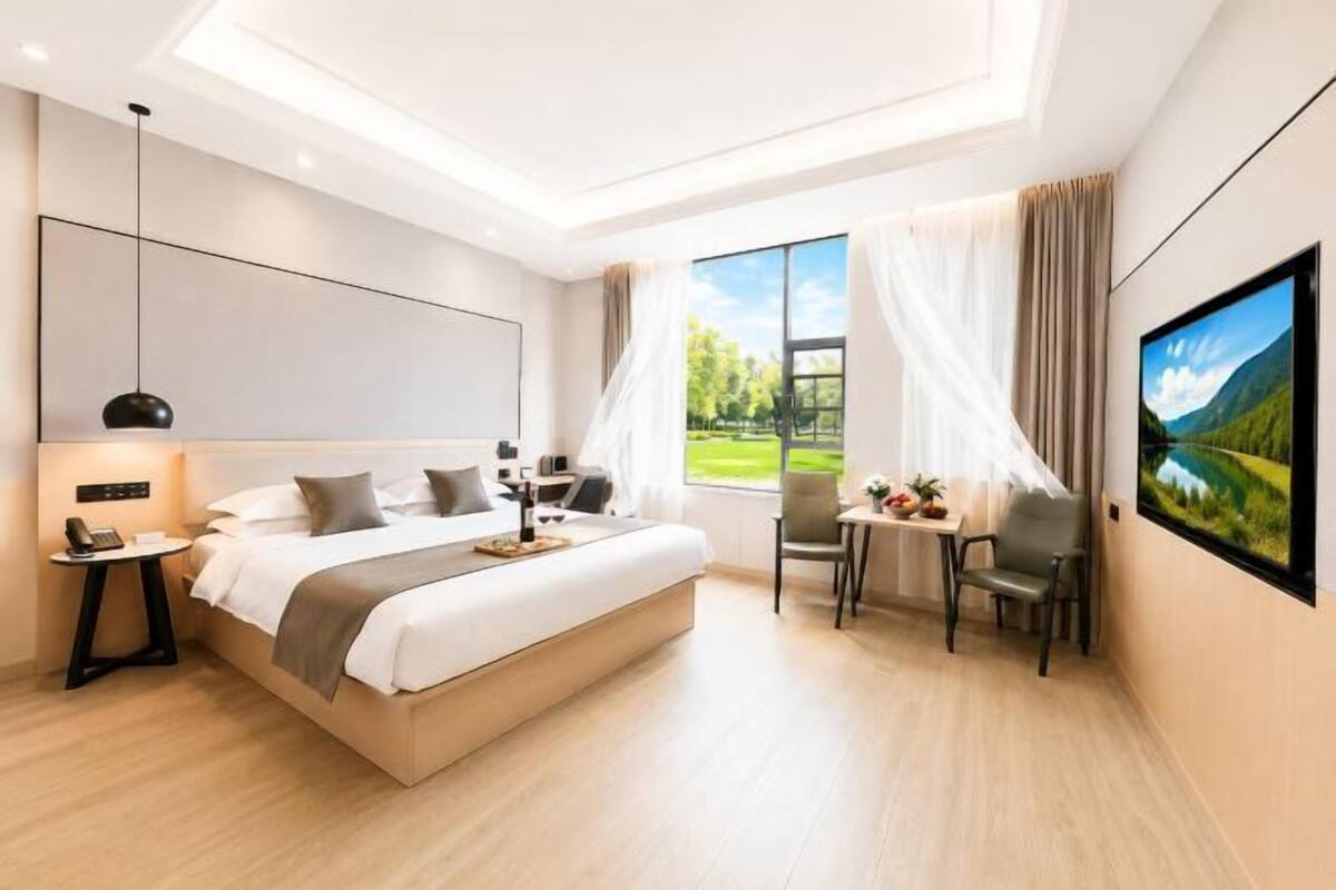 Ein modernes Hotelzimmer mit einem großen Bett, Nachttisch, Lampe und einem Fernseher an der Wand.