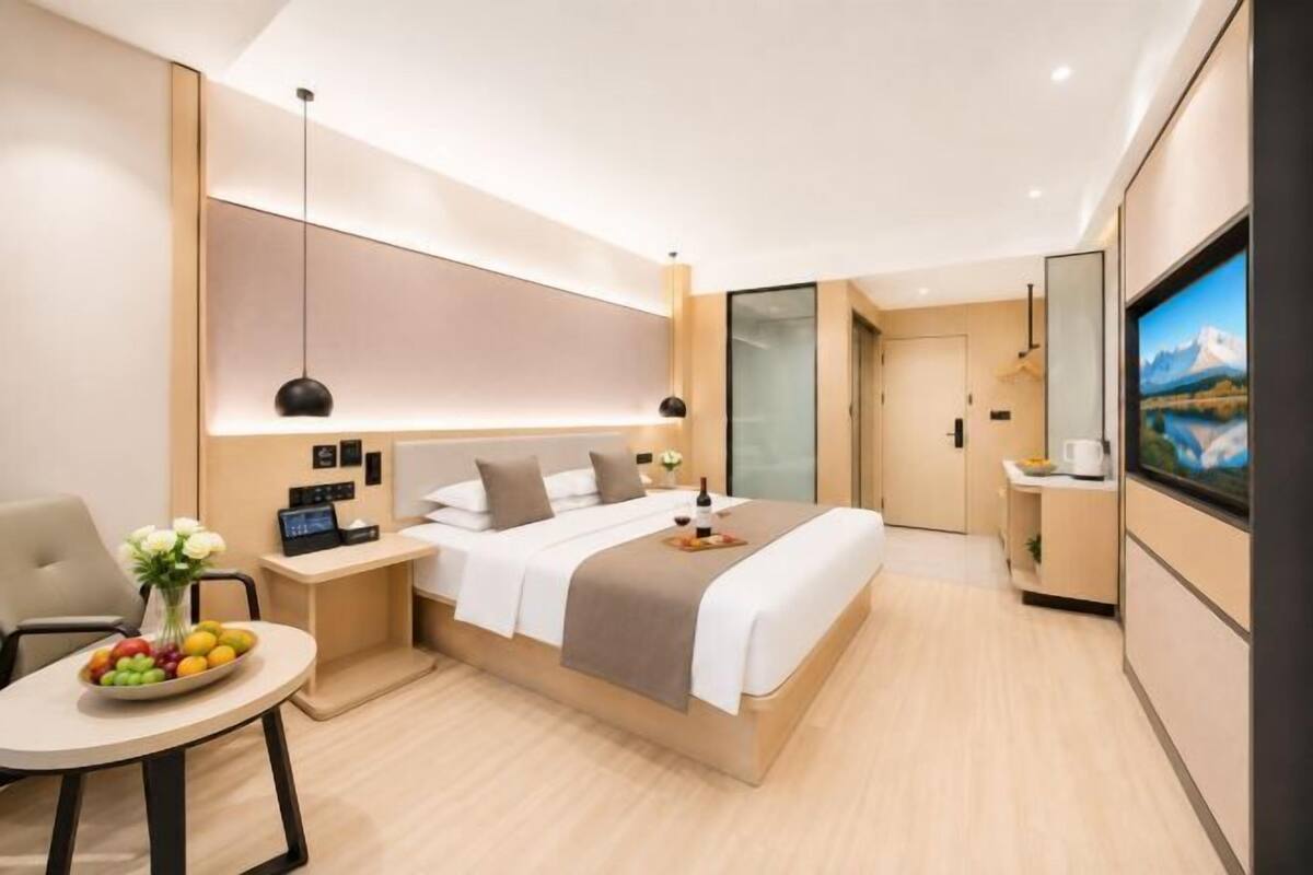 Ein modernes Hotelzimmer mit Bett, Nachttisch, Stuhl und einem Tisch mit Früchten.