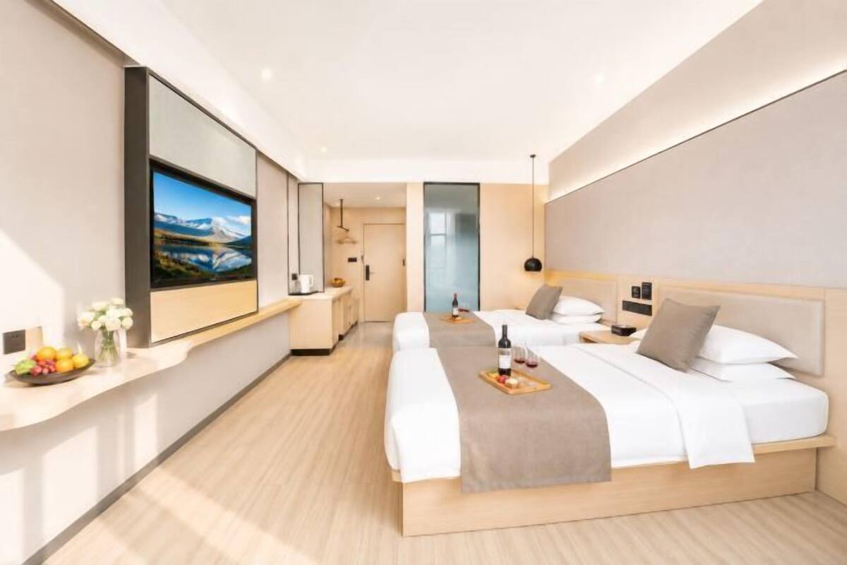 Ein modernes Hotelzimmer mit einem großen Bett, einem Fernseher, einem Schreibtisch und Blick auf eine Berglandschaft.
