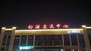 A building with illuminated signage reading "松滋客运中心" and a logo.