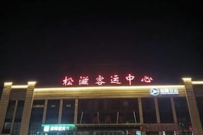 A building with illuminated signage reading "松滋客运中心" and a logo.