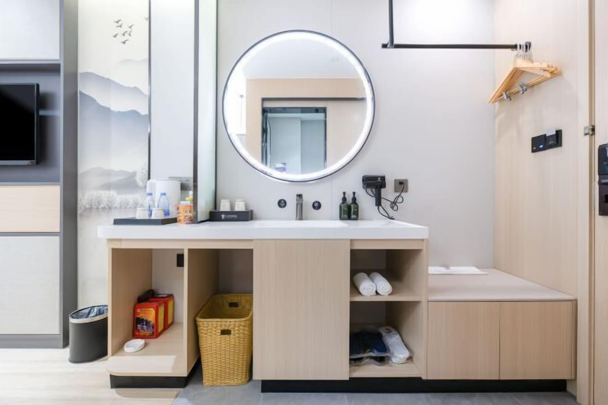 A modern bathroom with a round mirror, a sink, and storage cabinets.