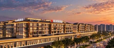 Et hotel i flere etager med moderne arkitektur, kendetegnet ved en markant indgang og en række balkoner.