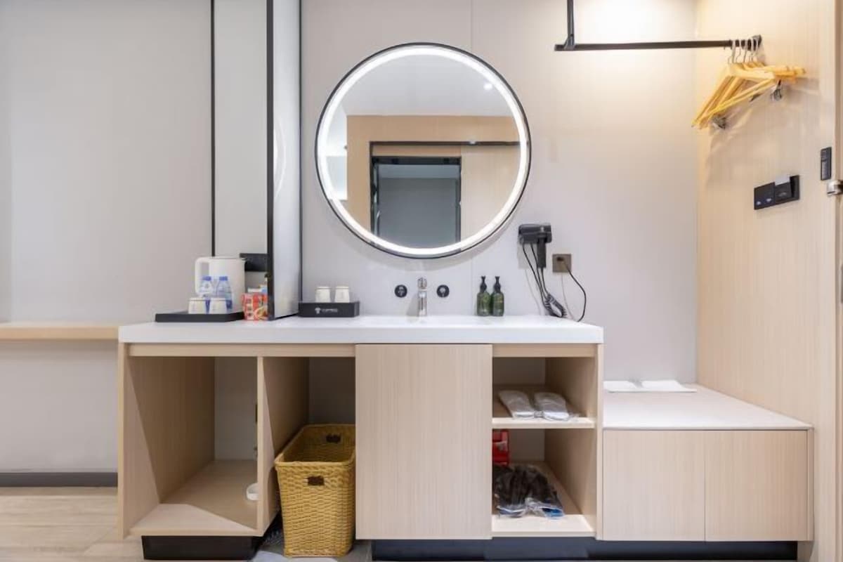 A modern bathroom with a round mirror, a sink, and built-in storage cabinets.