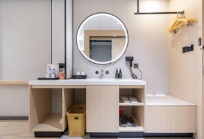 A modern bathroom with a round mirror, a sink, and built-in storage cabinets.