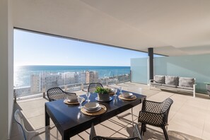 A modern dining area with a balcony overlooking the sea, featuring a table set with plates, glasses, and a centerpiece. - BEGOÑA SEA VIEW - Modern Apartment Just 5 Minutes from the Beach with Shared Pool and Fre (Fuengirola)