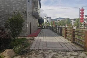 A paved pathway leading to a building with a red baseboard, a wooden fence, and red lanterns. - Shanghang Rongxiang Apartment (Shanghang)