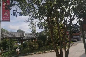 Ein traditionelles Gebäude mit Ziegeldach, umgeben von Bäumen und einem gepflasterten Weg.