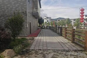 A paved pathway leading to a building with a red awning, a wooden fence, and red lanterns on the right. - Shanghang Rongxiang Apartment (Shanghang)