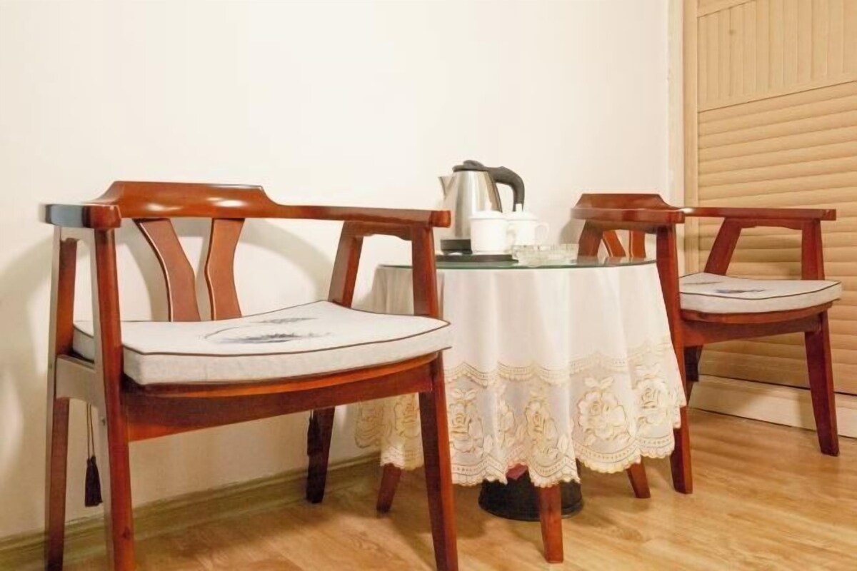 Un comedor con dos sillas de madera, una mesa de vidrio y un mantel blanco.