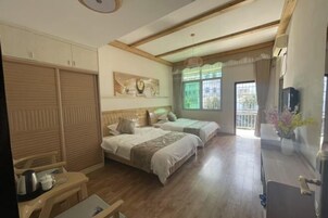 Habitación de hotel con dos camas, techo de madera, ventana con cortinas, televisión y escritorio con silla.