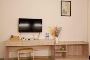 A modern room with a wooden desk, a flat-screen TV, a vase with flowers, and a framed artwork on the wall. - Shanghang Rongxiang Apartment (Shanghang)